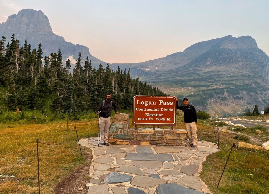 My Friend and I at the Continental Divide Sign - Logan Pass - Glacier National Park My Friend and I at the Continental Divide Sign - Logan Pass - Glacier National Park